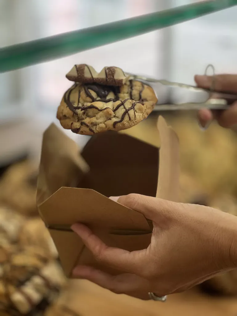 Mano con pinza sosteniendo una cookie metiéndola en una caja