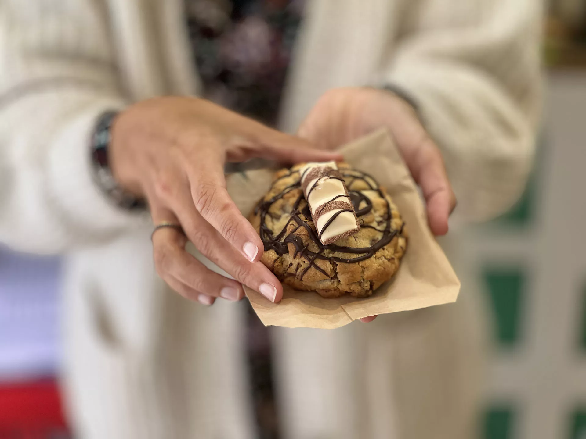 Mujer sosteniendo con ambas manos una cookie sobre una servilleta