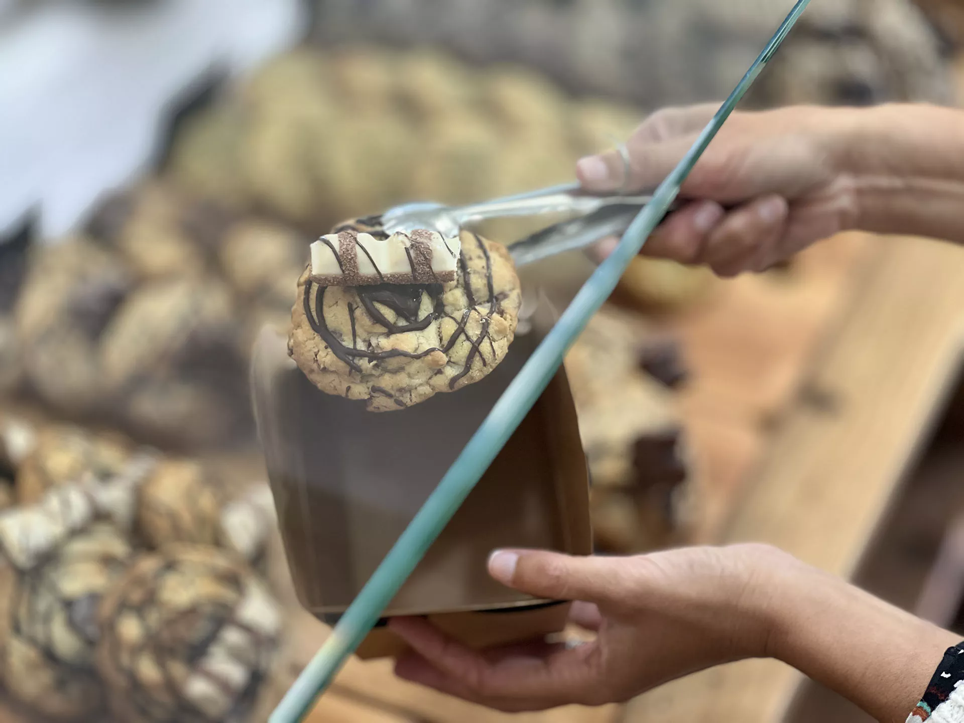 Mano con pinza sosteniendo cookies y una caja para guardarlas